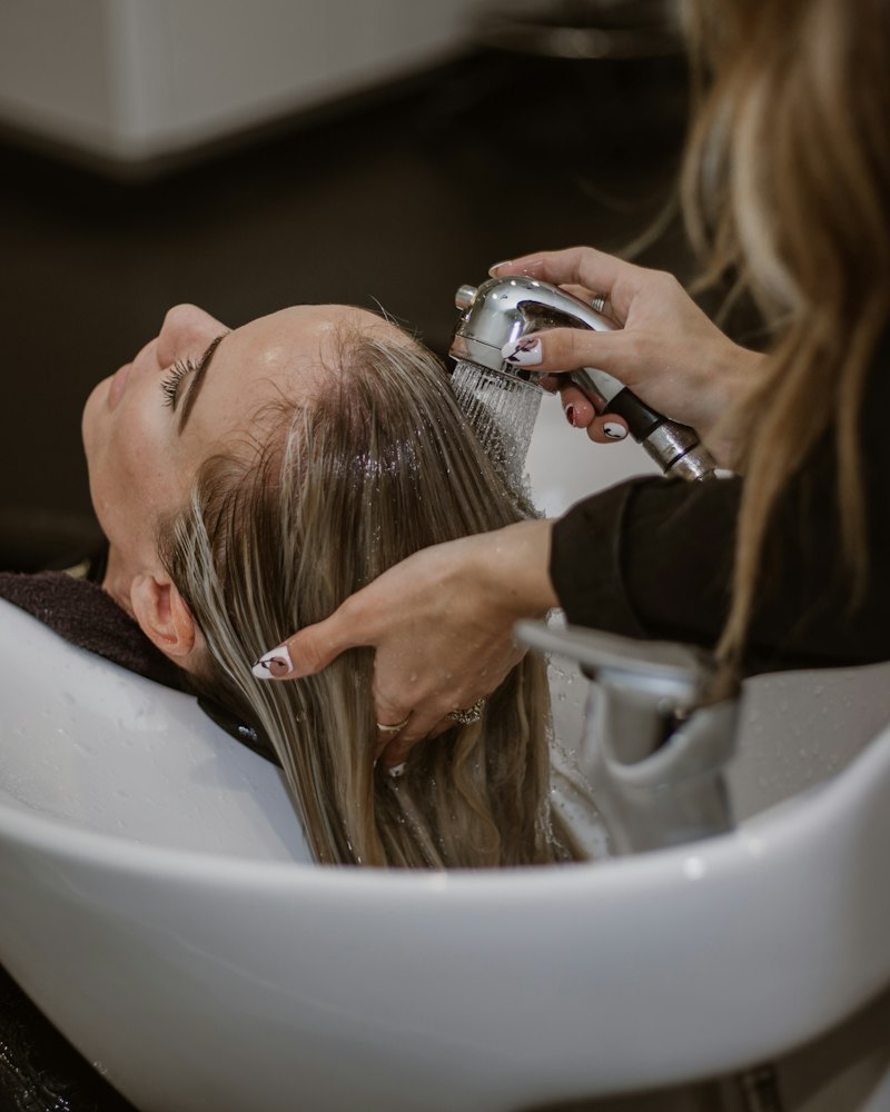 Stylist washing a client's hair at a salon basin