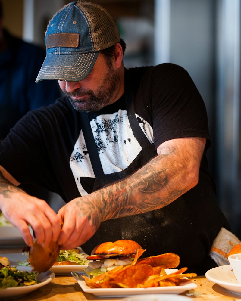 Chef plating food on the pass of a busy restaurant kitchen