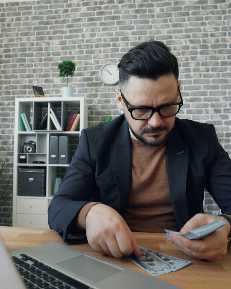 Professional reviewing figures at a desk beside a laptop