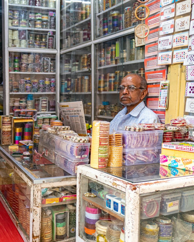 Shopkeeper behind the counter of a well-stocked independent shop